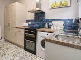 A kitchen with cabinets oven washing machine sink and blue tile backsplash at Fairways in Prestatyn