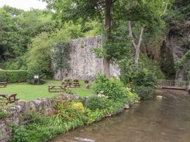A riverside garden with picnic tables flowers and trees by a stone wall at Riverlea in Dyserth