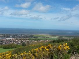 A coastal town with houses fields and sea with wind turbines offshore at Riverlea in Dyserth