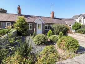 Front garden with bushes and a stone path in front of a bungalow with a white door at Riverlea in Dyserth