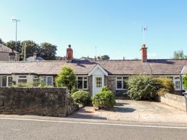 A single story house with a stone wall and shrubs in front at Riverlea in Dyserth