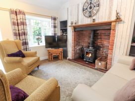 A living room with armchairs a sofa a wood burning stove and a television at Riverlea in Dyserth