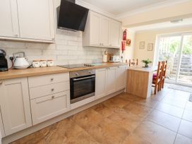 A kitchen with countertop appliances and a dining table near a glass door at Riverlea in Dyserth