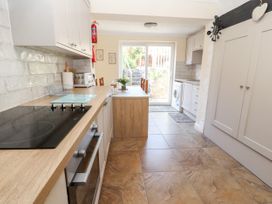 A kitchen with stove oven dining table chairs washing machine and sliding glass door at Riverlea in Dyserth