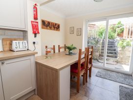 A kitchen dining area with a wooden table and chairs near glass sliding doors leading to a garden at Riverlea in Dyserth