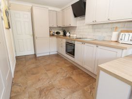 A kitchen with white cabinets brown tiled floor microwave toaster oven and stovetop at Riverlea in Dyserth