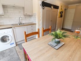 A kitchen with a wooden table and chairs a washing machine and a sink at Riverlea in Dyserth