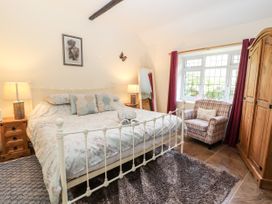 A bedroom with a bed side tables lamps a standing mirror an armchair and a wooden wardrobe at Riverlea in Dyserth