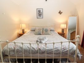 A bedroom with a double bed floral bedding two bedside tables with lamps a full length mirror and a framed picture at Riverlea in Dyserth