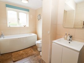 A bathroom with a bathtub toilet sink mirror and window at Riverlea in Dyserth