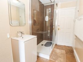A bathroom with a sink, mirror, shower area, and brown mat at Riverlea in Dyserth