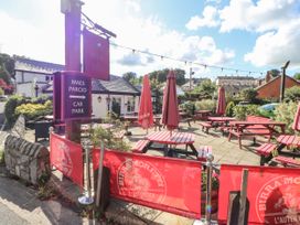 An outdoor seating area with red picnic tables and umbrellas at The New Inn with a sign for car park and red barriers with Birra Moretti branding