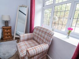 A living room with an armchair and a mirror at Riverlea in Dyserth