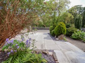 A garden with flowers, bushes, and stone features at Riverlea in Dyserth