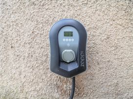 An electric vehicle charger mounted on a wall at Riverlea in Dyserth