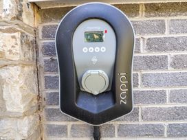 An electric vehicle charger mounted on a stone wall at Ty Cerrig in Dyserth