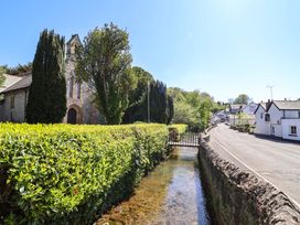 A church with a hedge and a stream next to a road at Ty Cerrig in Dyserth