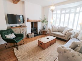 A living room with a sofa, armchair, and television at Harriet's Cottage in Briggswath