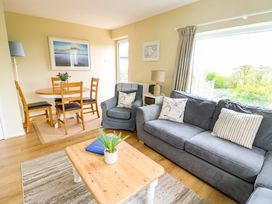 A living room with a sofa and dining area at Sea View in Benllech