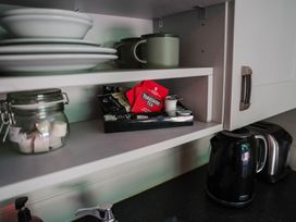 A kitchen shelf with plates, mugs, a jar of sugar, Yorkshire Tea and a kettle at Reflection in Longtown