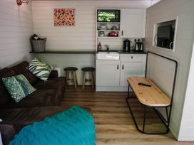 A living room with a sofa and kitchenette at Reflection in Longtown
