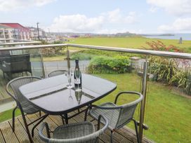 A balcony with a table and chairs overlooking a grassy area at Ocean Seven in Newquay