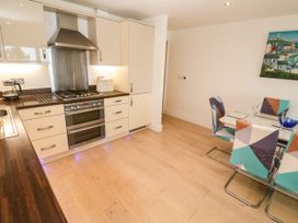 A kitchen with a stove, oven, sink, and dining area at Ocean Seven in Newquay