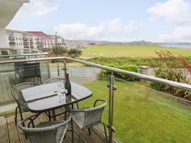 A balcony with a table and chairs overlooking a grassy area at Ocean Seven in Newquay