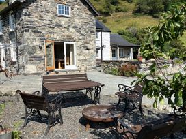 An outdoor seating area with a stone house at Peniarth Ganol in Tywyn