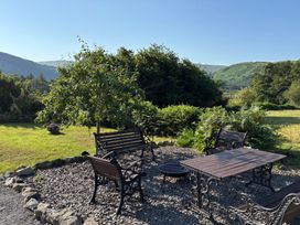 A garden with benches, a table, and trees at Peniarth Ganol in Tywyn