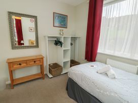 A bedroom with a bed, mirror, and clothing storage at Awelon Rhos-On-Sea