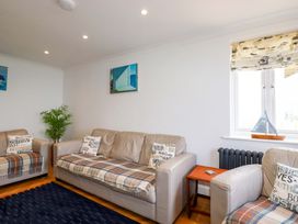 A sitting room with beige sofas and plaid blankets with cushions and a plant near the wall at Pink House in Mevagissey