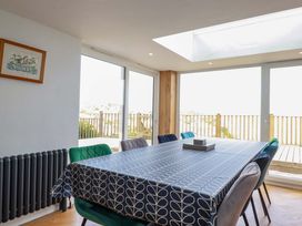 A dining room with a large table covered with a patterned tablecloth and chairs around it at Pink House in Mevagissey