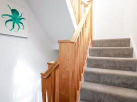 A staircase with wooden handrails and gray carpet at Pink House in Mevagissey