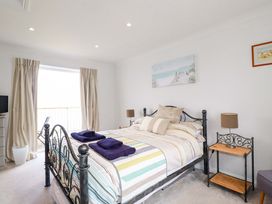 A bedroom with a metal bed frame and striped bedding with folded towels on the bed at Pink House in Mevagissey