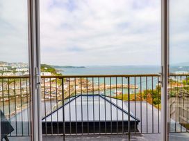 A balcony with metal railing overlooking a coastal town with boats in the harbor at Pink House in Mevagissey