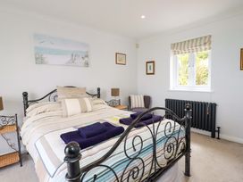 A bedroom with a metal bed frame striped bedding two folded towels bedside tables and a window with blinds at Pink House in Mevagissey