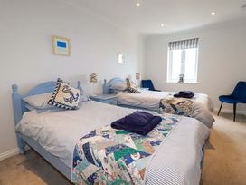 A bedroom with two single beds blue headboards striped bedding patchwork quilts and blue chairs at Pink House in Mevagissey