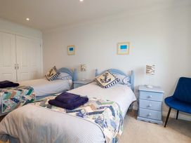 A bedroom with two single beds blue headboards blue pillows and folded towels at Pink House in Mevagissey