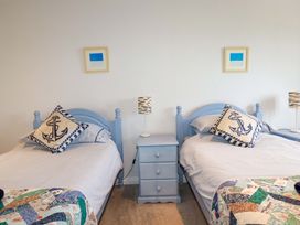 A bedroom with two blue beds separated by a blue nightstand with a lamp at Pink House in Mevagissey