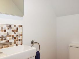 A bathroom sink with mosaic tile backsplash and a towel ring with a dark towel at Pink House in Mevagissey