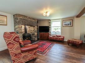 A living room with a fireplace and seating at Plas Mawr in Groeslon