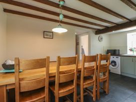 A kitchen with a wooden dining table and chairs at Plas Mawr Groeslon