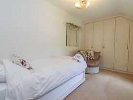 A bedroom featuring a bed, a cushion, a mirror, and a wardrobe at Plas Mawr in Groeslon