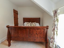 A bedroom with a wooden bed and a door at Plas Mawr in Groeslon