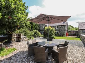 A garden with a table and chairs under an umbrella at Plas Mawr Groeslon