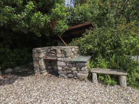 An outdoor area with a stone barbecue and a bench at Plas Mawr in Groeslon