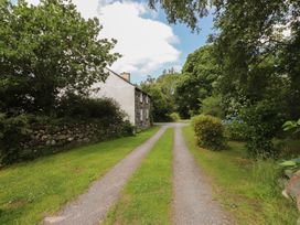 A driveway leading to a house surrounded by trees at Plas Mawr in Groeslon
