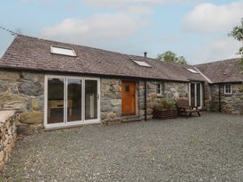 An outdoor area with a stone building and sliding glass doors at Beudy'r Wennol Groeslon