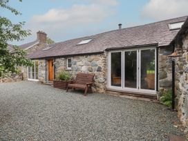 An outdoor area with a wooden bench and stone walls at Beudy'r Wennol, Groeslon